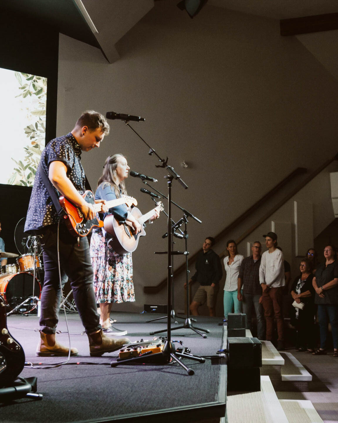 Worship band with church members in the background worshiping